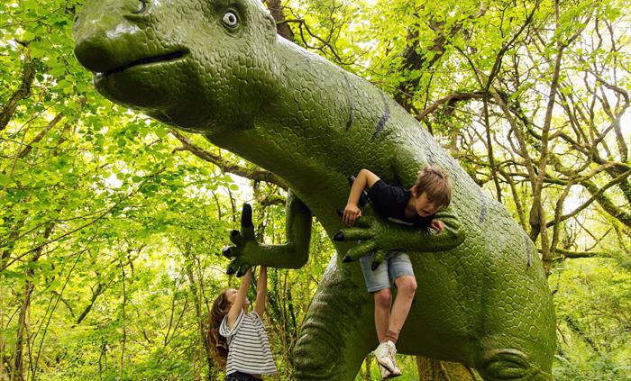 Two children hanging off a huge Dinosaur on the Dinosaur Trail